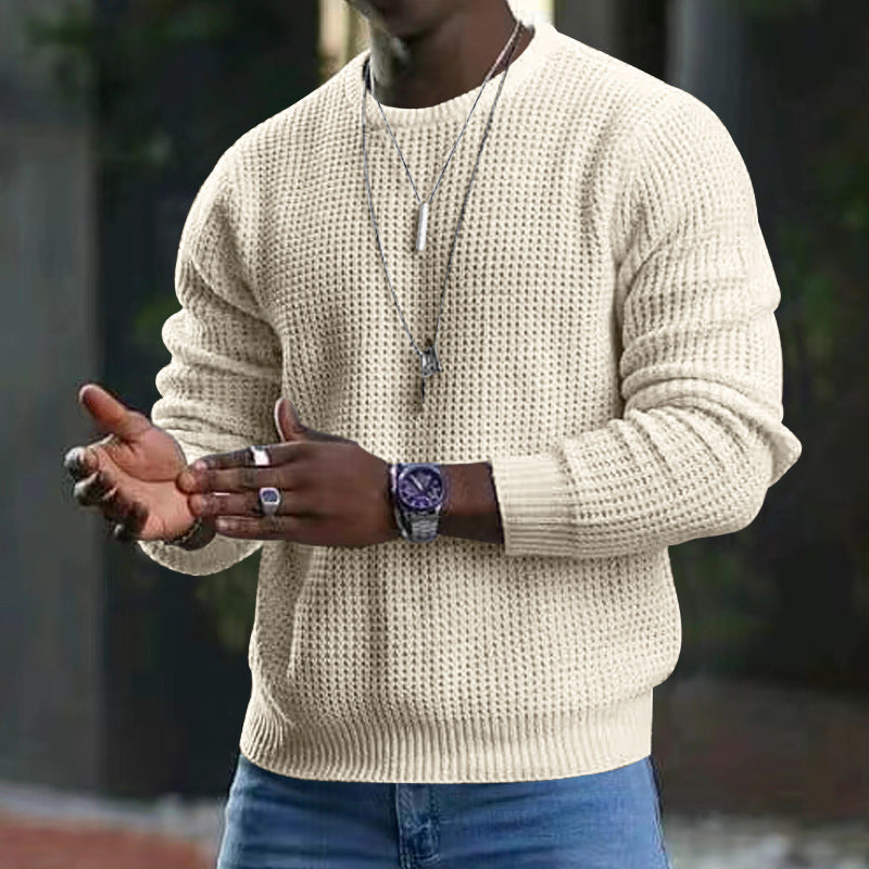 Uomo con maglione a maglia beige, orologio elegante e collane, in posa all'aperto. Moda maschile autunnale, accessori trendy.
