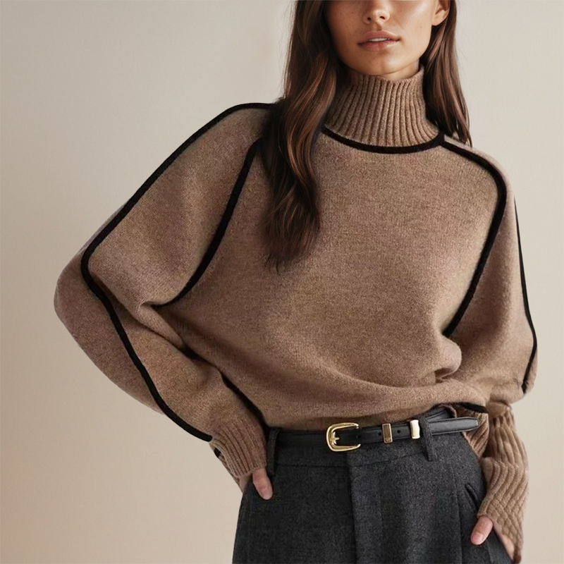 Donna con maglione marrone a collo alto, dettagli neri, pantaloni grigi. Moda autunnale elegante, stile casual chic, abbigliamento femminile moderno.
