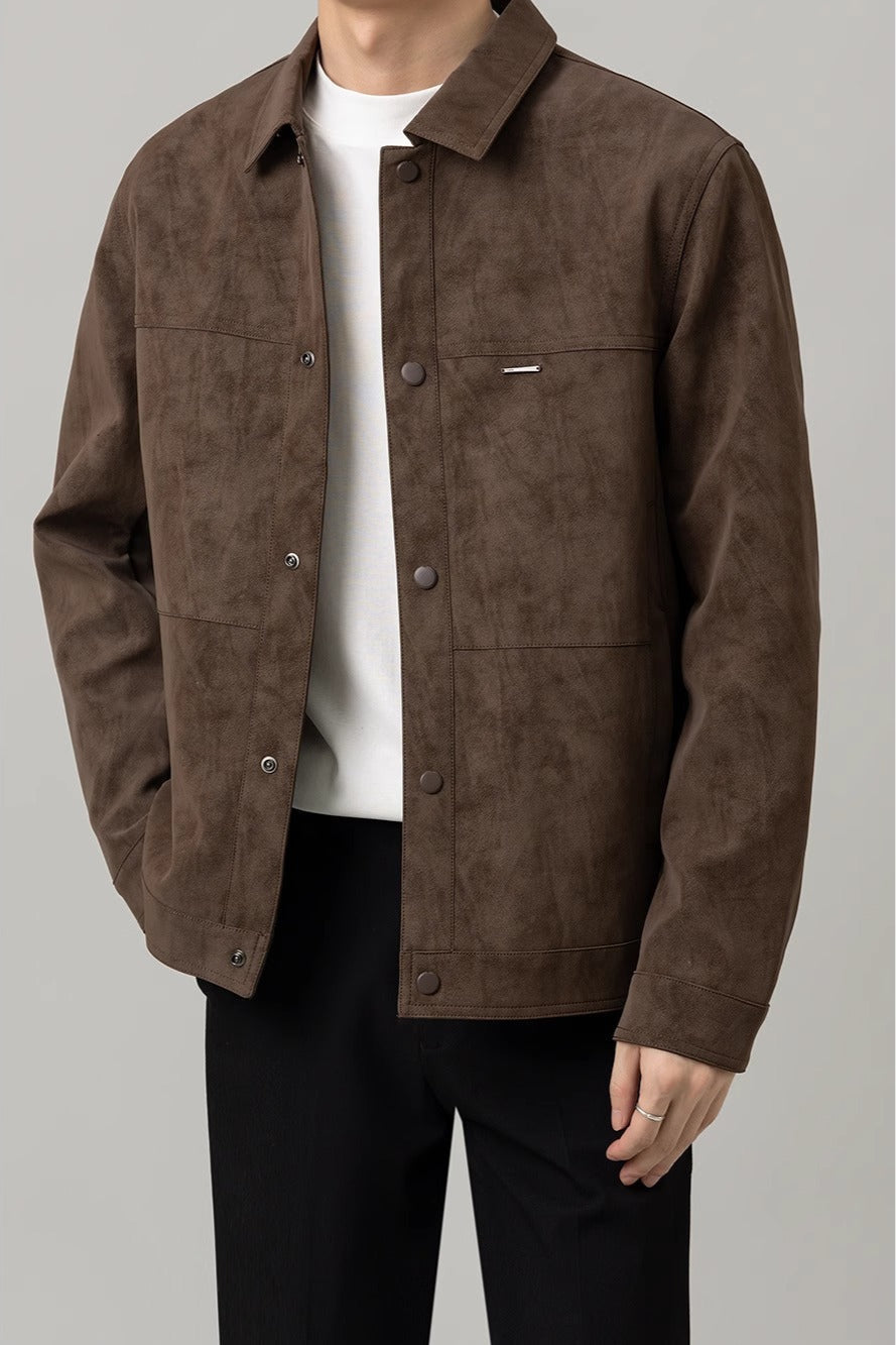 Giacca marrone in pelle scamosciata da uomo, stile casual, con bottoni frontali e tasche, indossata su maglietta bianca e pantaloni neri.