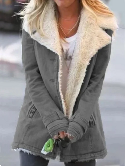 Donna con cappotto invernale grigio con fodera in pelliccia sintetica bianca, indossa jeans e tiene chiavi. Moda autunnale, abbigliamento casual.