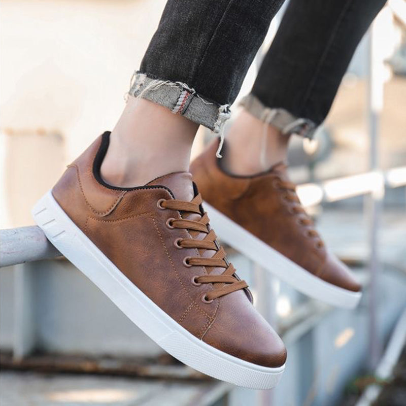Scarpe da ginnastica marroni in pelle, suola bianca, indossate con jeans strappati. Stile casual, moda urbana, calzature trendy per giovani.