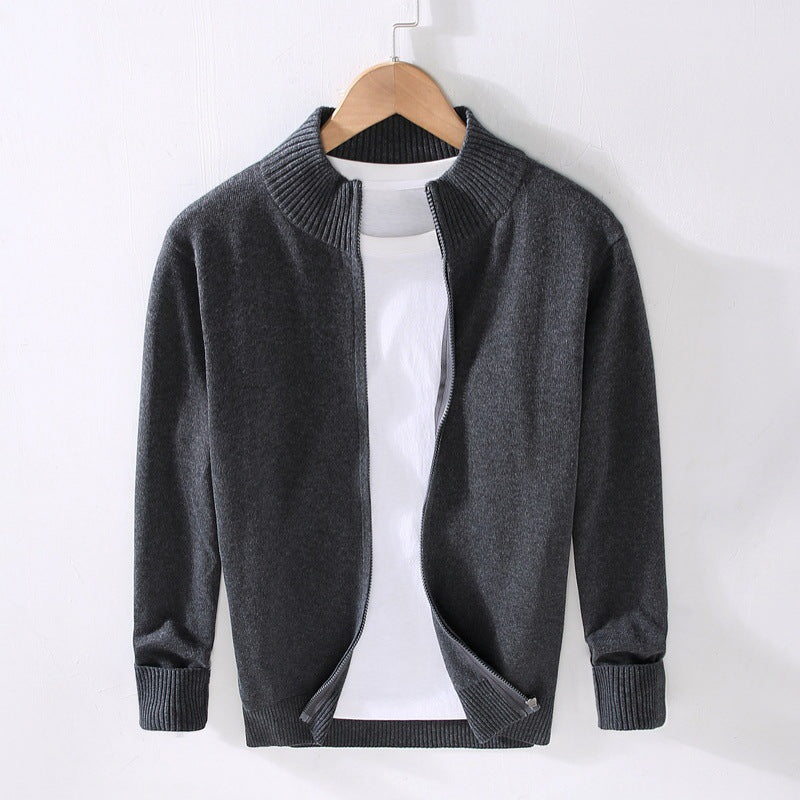 Cardigan grigio scuro in lana su appendiabiti, con zip aperta e maglietta bianca sotto. Moda uomo, abbigliamento casual elegante.