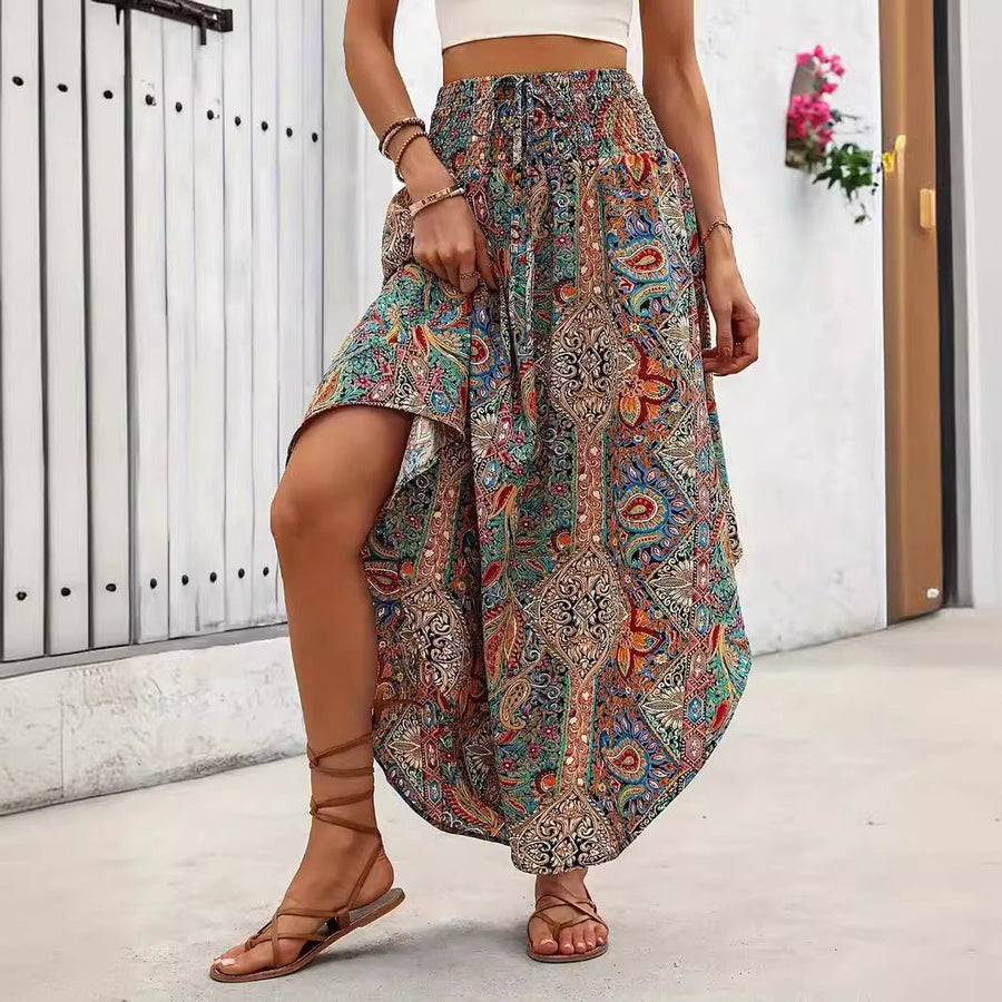 Donna con gonna lunga boho a fantasia colorata, sandali marroni, top bianco. Moda estiva, stile casual, abbigliamento femminile trendy.