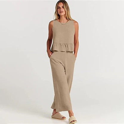 Donna in abbigliamento estivo beige, top senza maniche e pantaloni larghi, sandali chiari. Moda casual elegante, look estivo femminile.
