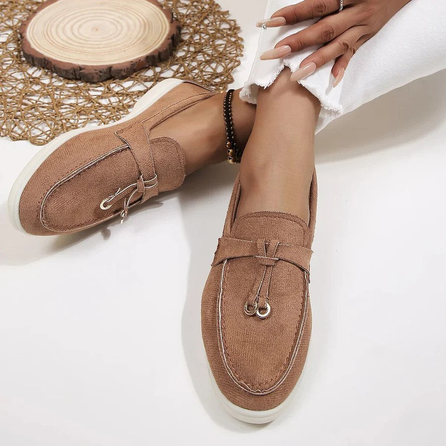 Scarpe mocassini donna in tessuto beige, suola bianca, indossate con jeans bianchi. Design elegante e casual, perfette per la moda primaverile.