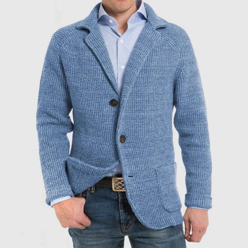 Giacca uomo blu in maglia, stile casual, con bottoni e tasche frontali, indossata su camicia azzurra e jeans. Moda maschile elegante.