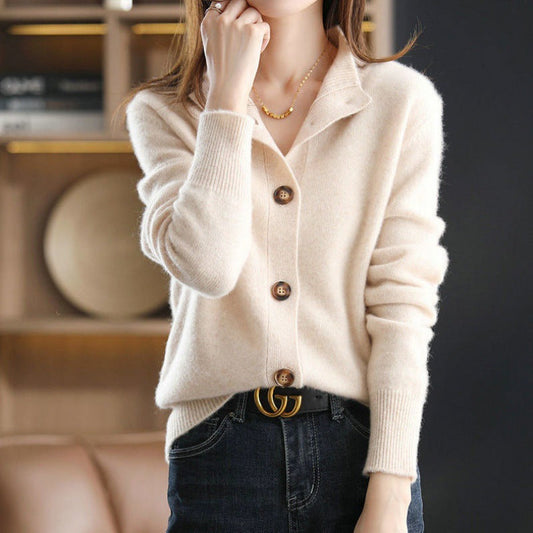 Donna indossa cardigan beige in cashmere con bottoni, abbinato a jeans scuri e cintura di marca. Look elegante e casual per l'autunno.