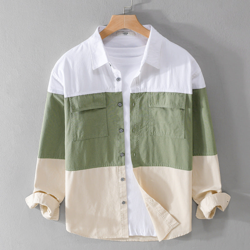 Camicia casual a blocchi di colore verde, bianco e beige, con tasche frontali e maniche lunghe, appesa su gruccia di legno. Moda uomo autunno.