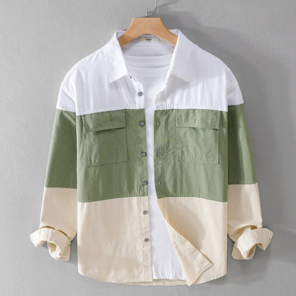 Camicia casual a blocchi di colore verde, bianco e beige, con tasche frontali e maniche lunghe, appesa su gruccia di legno. Moda uomo autunno.