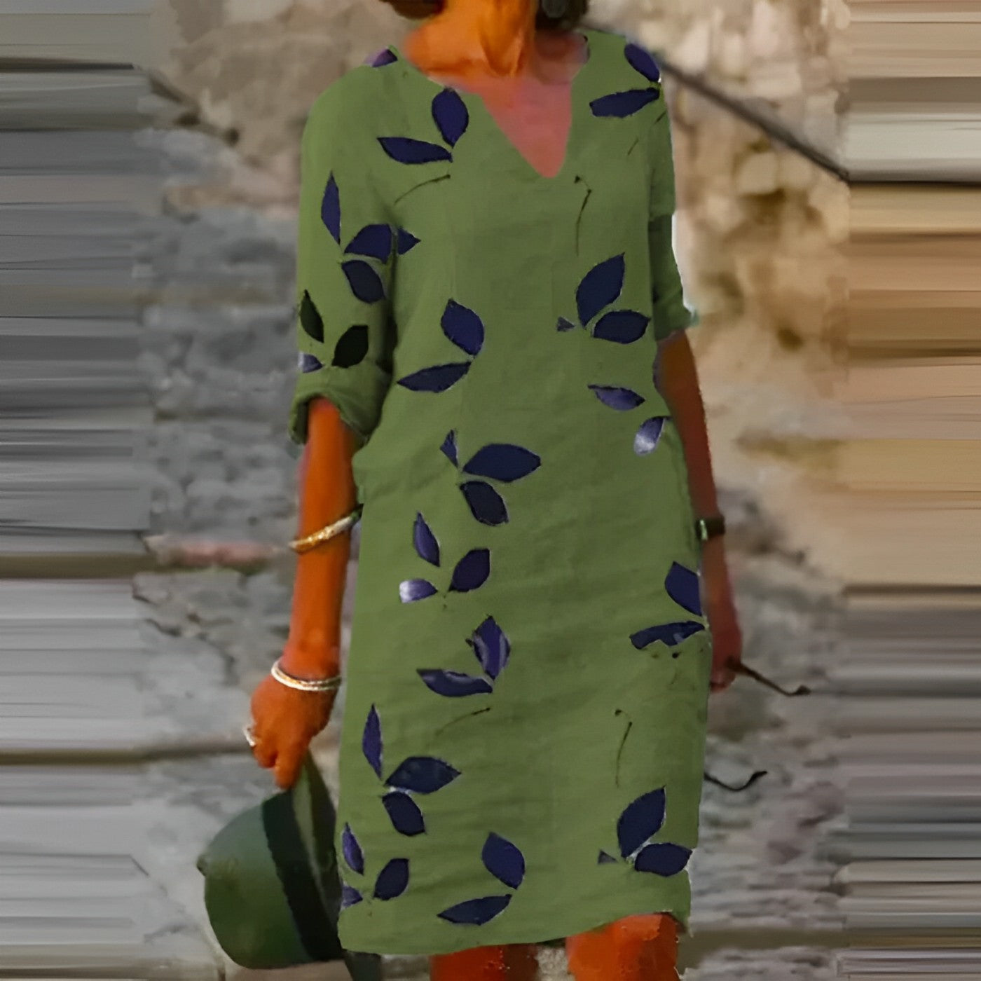 Donna con abito verde a foglie blu, maniche arrotolate, cammina su strada acciottolata. Moda estiva, stile casual, accessori argento.