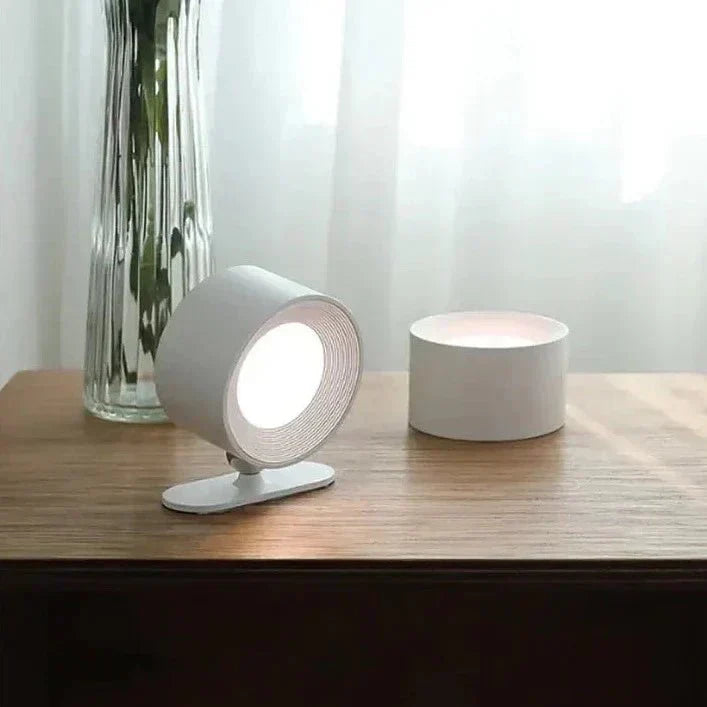 Lampada da tavolo moderna bianca su scrivania in legno, design minimalista, luce LED, vaso di fiori in vetro sullo sfondo, arredamento elegante.
