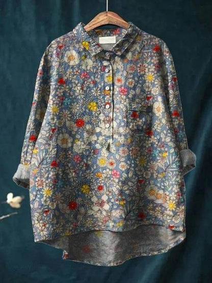 Camicia donna floreale vintage, maniche lunghe, colletto classico, sfondo blu, motivi fiori colorati, moda casual, abbigliamento primaverile.