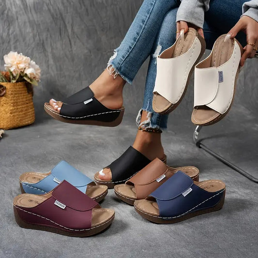 Donna con sandali ortopedici colorati, comodi e alla moda, su sfondo grigio. Scarpe estive con zeppa, ideali per passeggiate e relax.