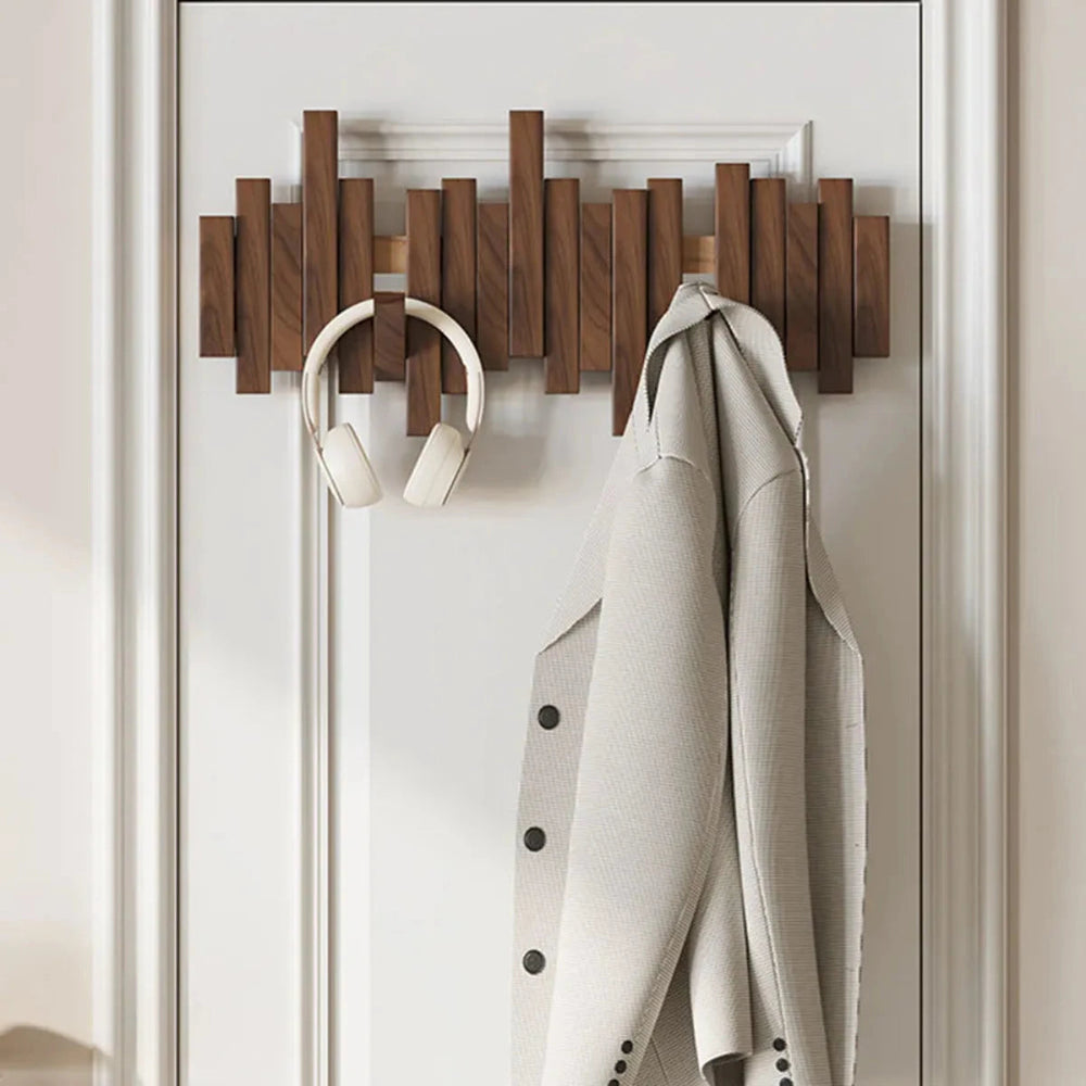 Appendiabiti moderno in legno su porta bianca con cuffie e giacca beige. Design elegante, organizzazione casa, accessori pratici.