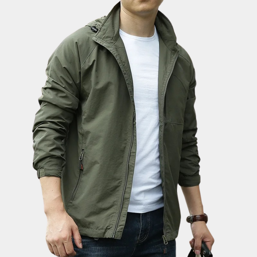 Giacca verde militare da uomo, casual e leggera, con zip e tasche, indossata sopra una maglietta bianca. Ideale per look autunnali e primaverili.