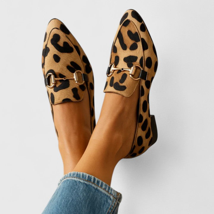 Scarpe mocassini leopardate da donna con fibbia dorata, indossate con jeans. Stile elegante e moderno, perfetto per look casual e chic.