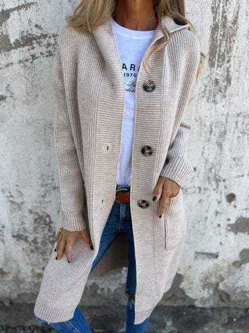 Donna con cardigan beige lungo, bottoni grandi, indossa jeans e maglietta bianca. Moda autunnale casual, abbigliamento femminile elegante.