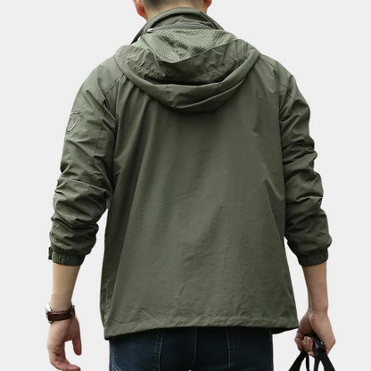 Giacca verde militare con cappuccio, indossata da uomo di spalle. Design casual, tessuto leggero, ideale per moda urbana e outdoor.
