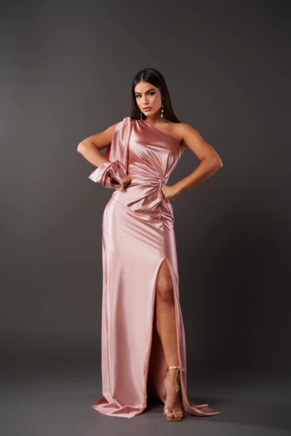 Donna in abito da sera rosa satinato con spacco alto, posa elegante su sfondo grigio. Moda femminile, abbigliamento elegante, tendenze 2023.