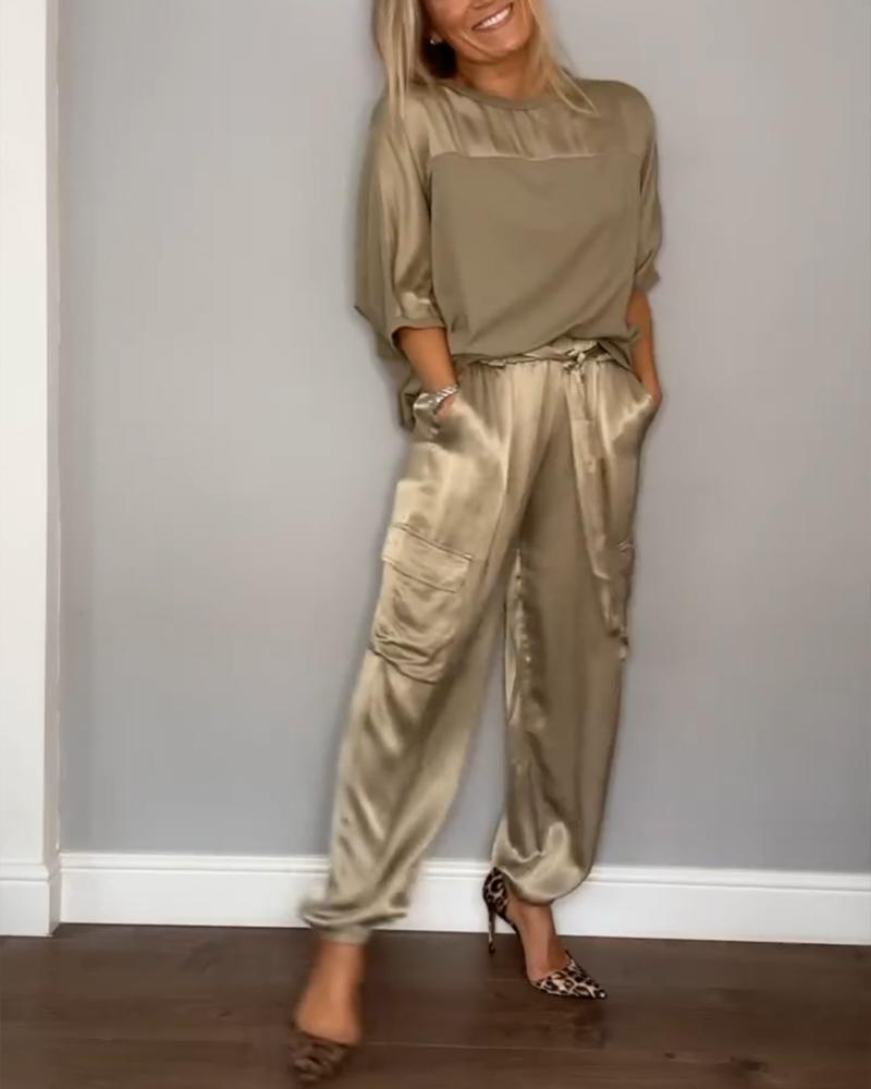 Donna in tuta di seta beige con tasche cargo, maniche lunghe, scarpe leopardate. Moda elegante, abbigliamento casual chic, stile autunnale.