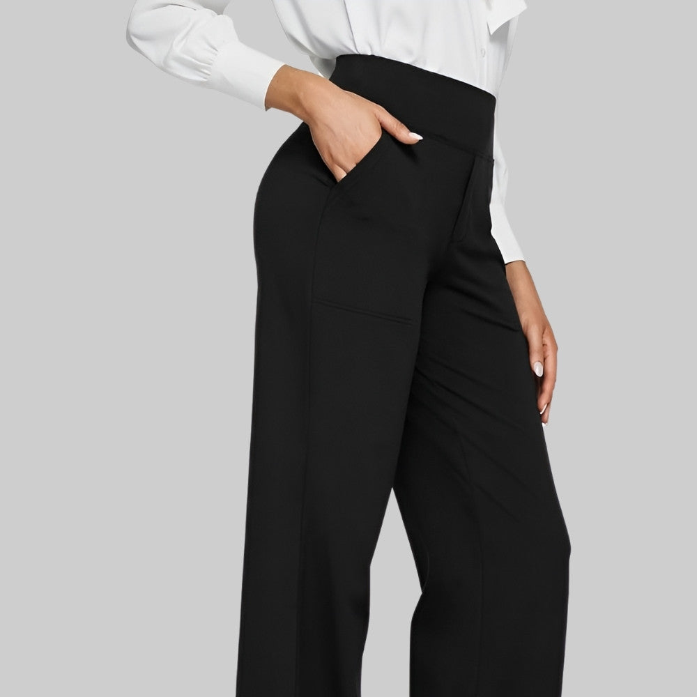 Donna in camicia bianca e pantaloni neri eleganti con tasche, posa su sfondo grigio. Moda femminile, abbigliamento da ufficio, stile professionale.