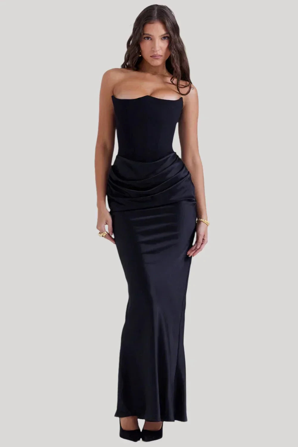 Donna in abito lungo nero elegante, senza spalline, con drappeggio in vita. Moda femminile, abbigliamento da sera, stile sofisticato.
