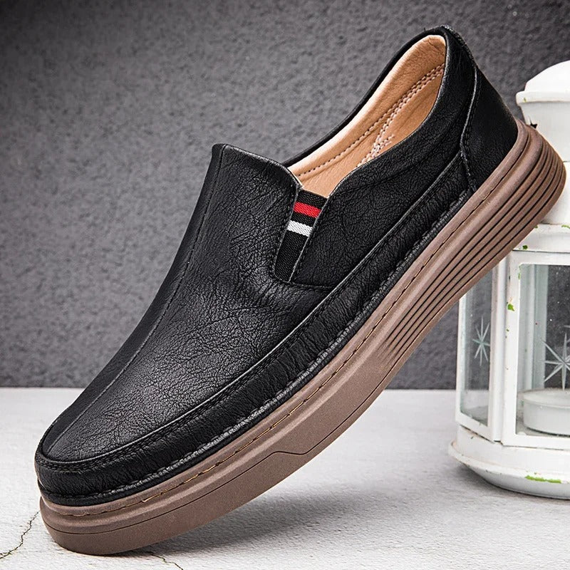 Scarpa mocassino uomo in pelle nera con suola marrone, design elegante e casual, perfetta per look quotidiani. Accessorio moda maschile.