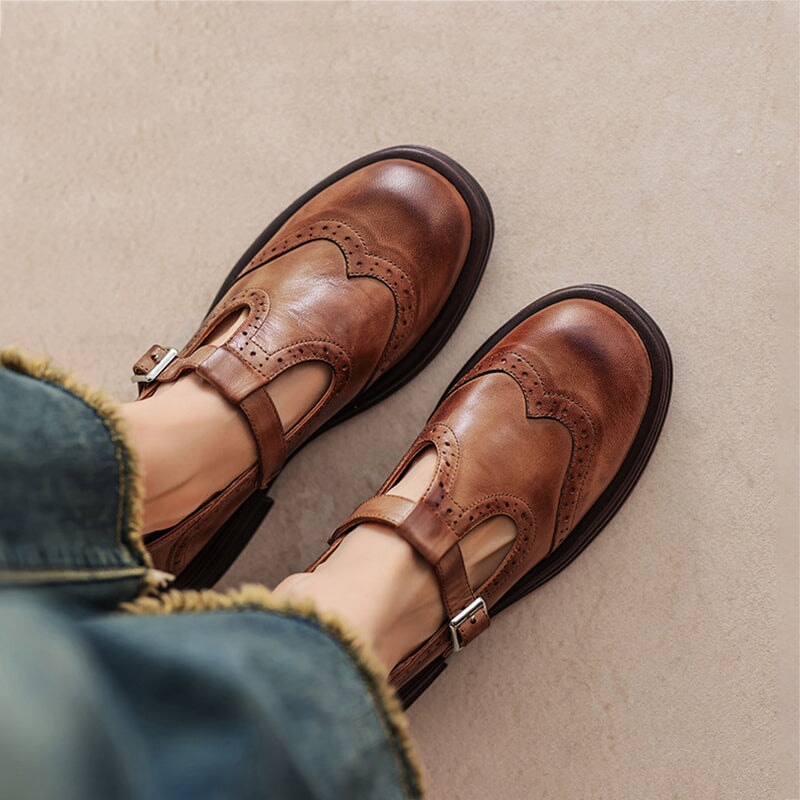 Scarpe in pelle marrone con fibbia, design vintage, indossate con jeans. Scarpe eleganti e casual, ideali per moda autunnale.