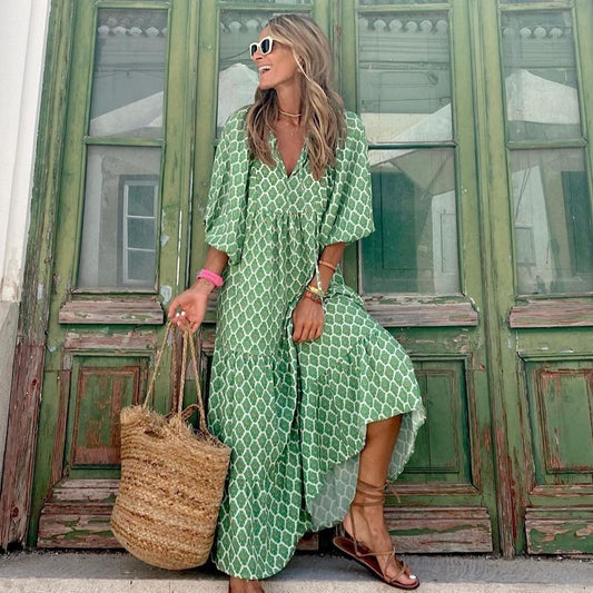 Donna con abito verde a fantasia geometrica, occhiali da sole bianchi, borsa di paglia, davanti a porta verde. Moda estiva, stile boho chic.