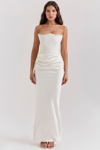 Donna in abito da sera bianco lungo, senza spalline, con drappeggio in vita. Elegante vestito da cerimonia, moda femminile, stile sofisticato.