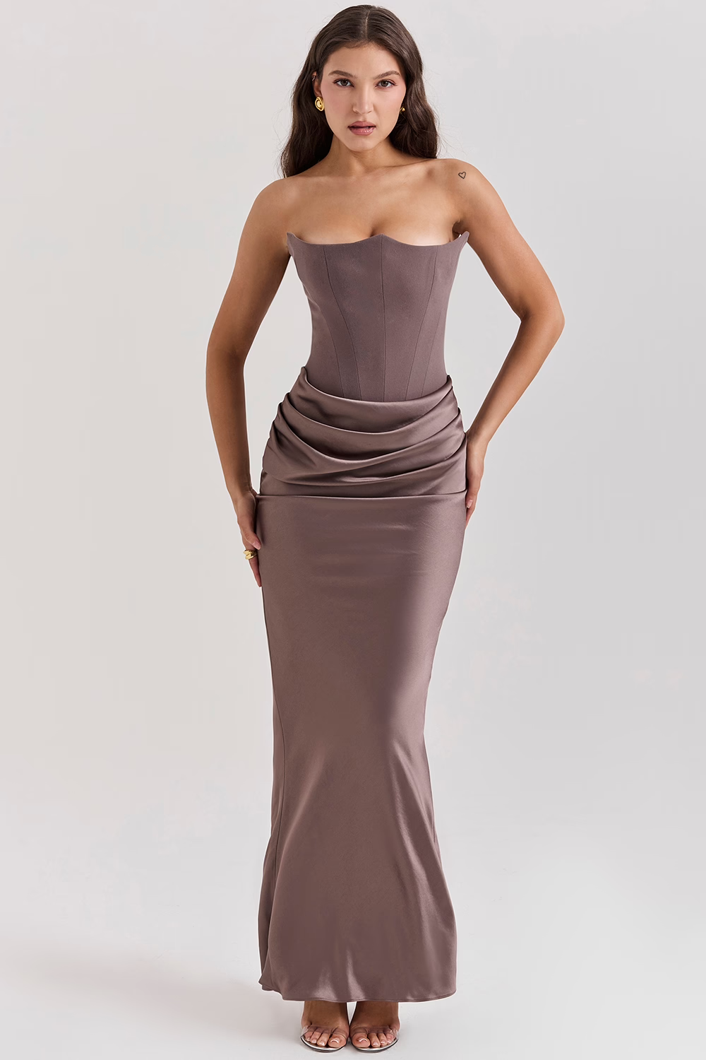 Donna in abito lungo elegante color taupe, senza spalline, con drappeggio in vita. Moda femminile, abbigliamento da sera, stile sofisticato.