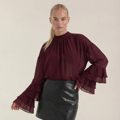 Blusa de mujer color burdeos de gasa transparente con mangas con volantes y cuello alto.