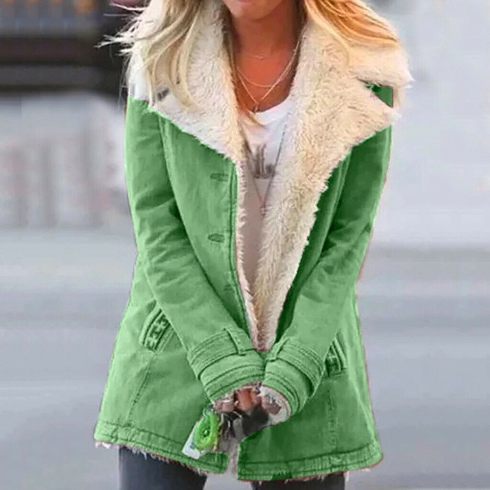 Donna con cappotto verde invernale con fodera in pelliccia sintetica bianca, sfondo urbano sfocato. Moda femminile, abbigliamento caldo.