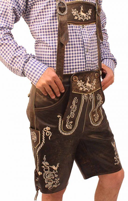 Uomo in camicia a quadri blu e bianchi indossa Lederhosen tradizionali bavaresi marroni con ricami bianchi, abbigliamento tipico Oktoberfest.
