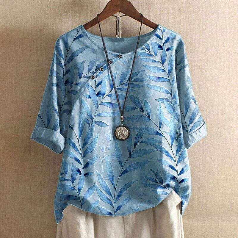 Maglietta donna blu con motivo foglie, bottoni decorativi, maniche corte e collana pendente. Moda casual estiva, abbigliamento femminile elegante.