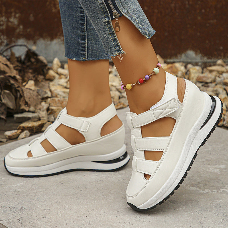 Sandali bianchi con zeppa, cinturini regolabili e suola antiscivolo indossati con jeans strappati. Accessorio cavigliera colorata. Moda estiva casual.