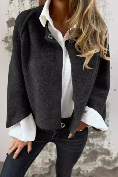 Donna con giacca nera elegante su camicia bianca, jeans scuri. Moda autunnale, stile casual chic, abbigliamento femminile moderno.