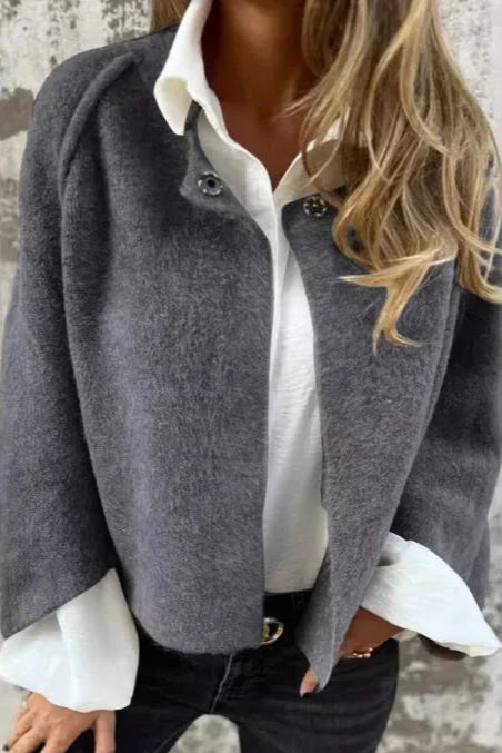 Donna con cappotto grigio elegante, camicia bianca e jeans neri. Moda autunnale, abbigliamento casual chic, stile contemporaneo.
