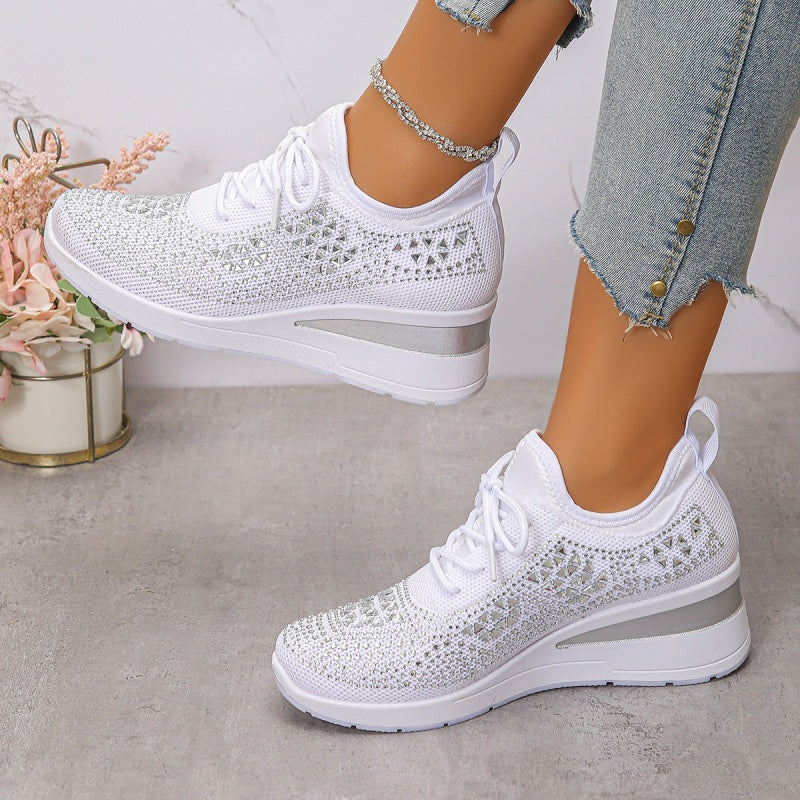 Scarpe da ginnastica bianche da donna con zeppa, dettagli in pizzo, indossate con jeans strappati. Scarpe moda casual eleganti e comode.