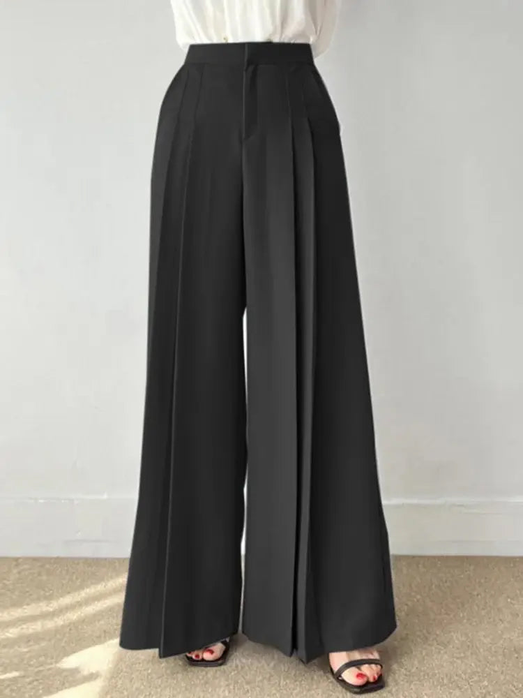 Pantaloni palazzo neri eleganti, vita alta, tessuto fluido, abbinati a camicia bianca. Moda donna, abbigliamento formale, stile sofisticato.