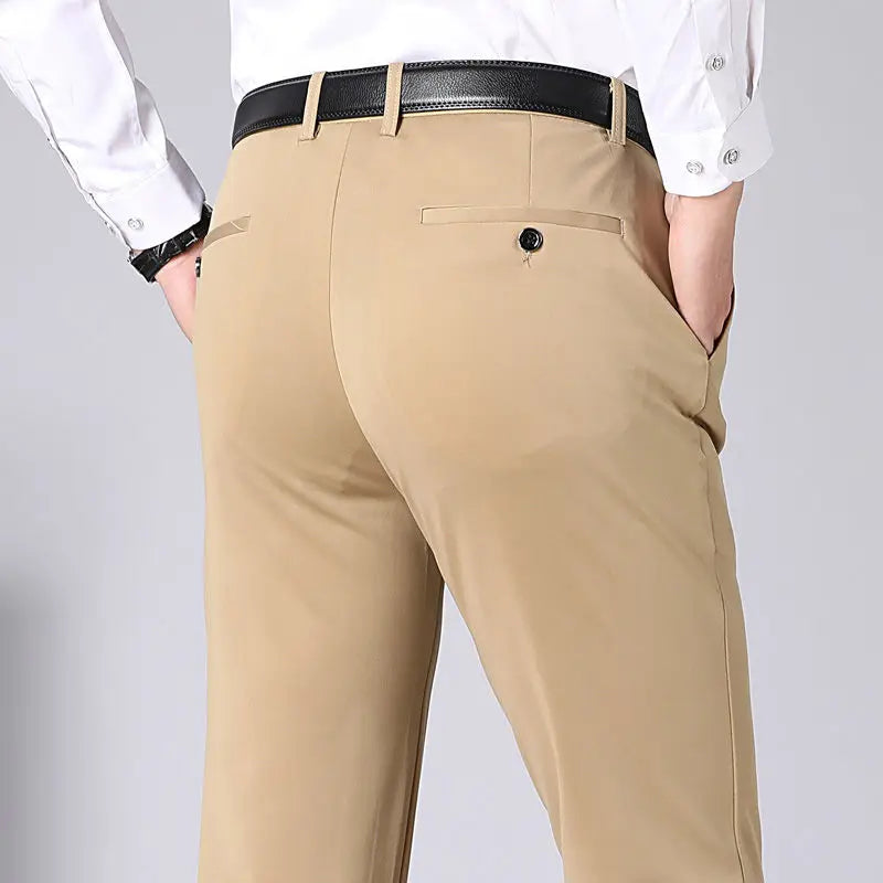 Pantaloni eleganti beige da uomo, tasche posteriori con bottoni, camicia bianca, cintura nera. Moda maschile, abbigliamento formale.