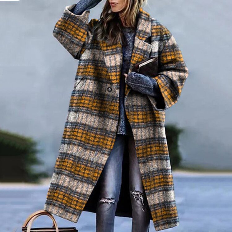 Donna con cappotto a quadri giallo e grigio, maglione blu, jeans strappati, borsa marrone. Moda invernale, stile casual chic.